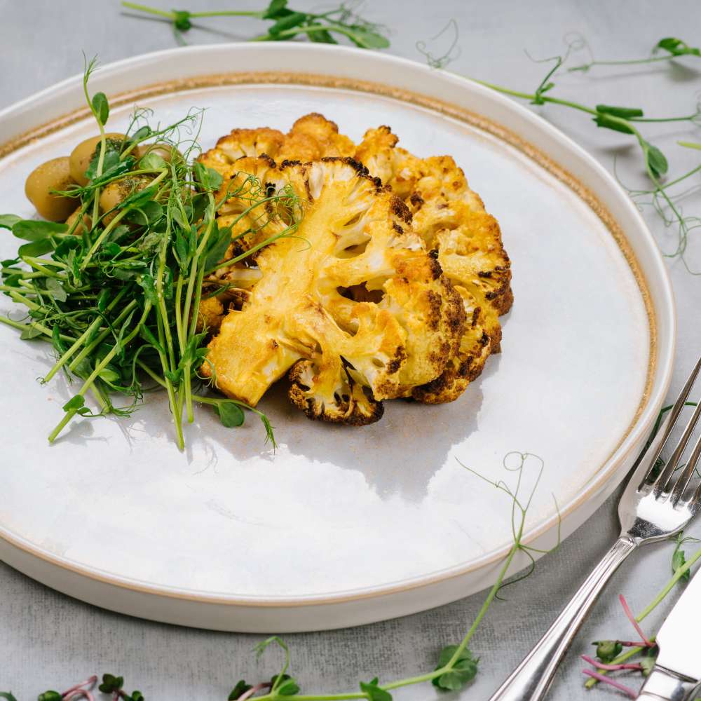 Grilled cauliflower dish with olives microgreens vegan menu 1