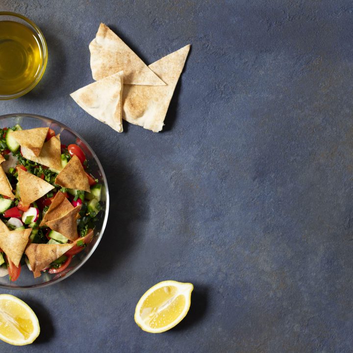 Traditional fattoush salad with vegetables pita bread levantine arabic middle eastern cuisine served glass plate with lemon pita olive oil dark background top view space text min