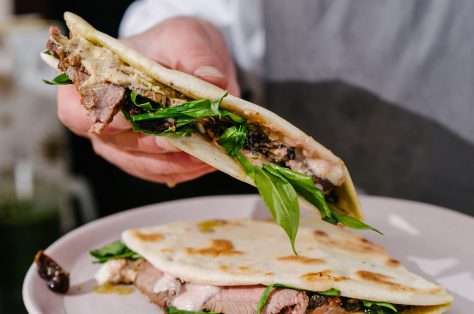 Italian piadina chef39s hands with roast beef wild garlic sundried tomatoes pesto mozzarella bechamel sauce